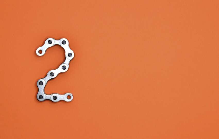 Metal chain forming the number 2 on a bright orange background, perfect for design projects.