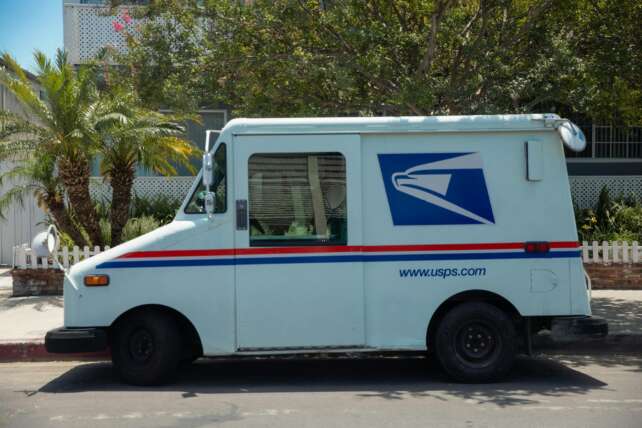 United States Postal Service van parked in a residential area on a bright sunny day.