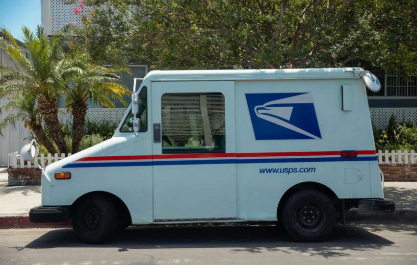 United States Postal Service van parked in a residential area on a bright sunny day.