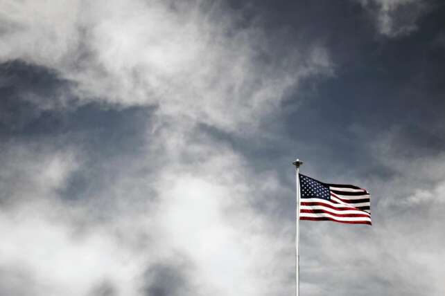 Vibrant American flag waving against a striking cloudy sky, symbolizing freedom and patriotism.