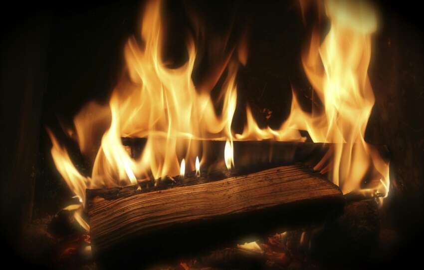 Close-up of a cozy fireplace with vibrant flames and firewood for warmth.