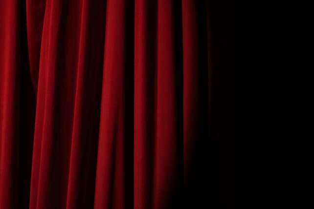 Elegant red velvet curtain with dramatic lighting perfect for theater themes.