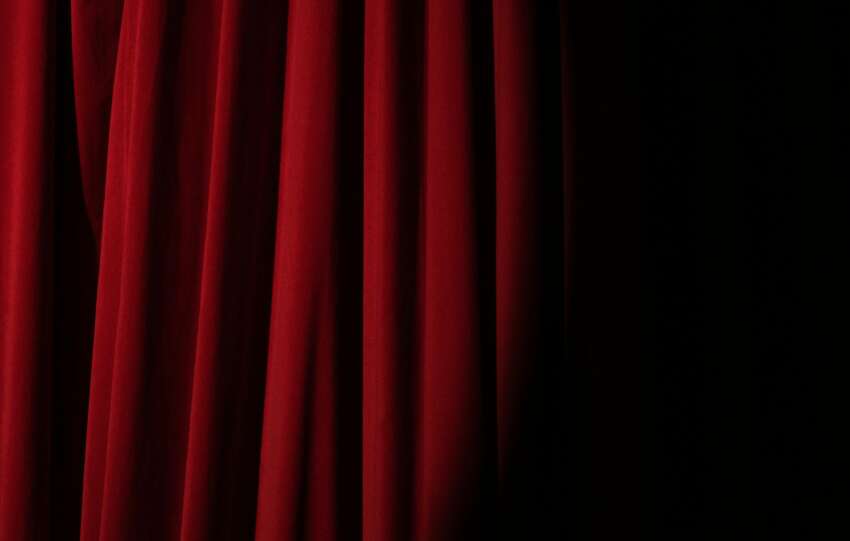 Elegant red velvet curtain with dramatic lighting perfect for theater themes.