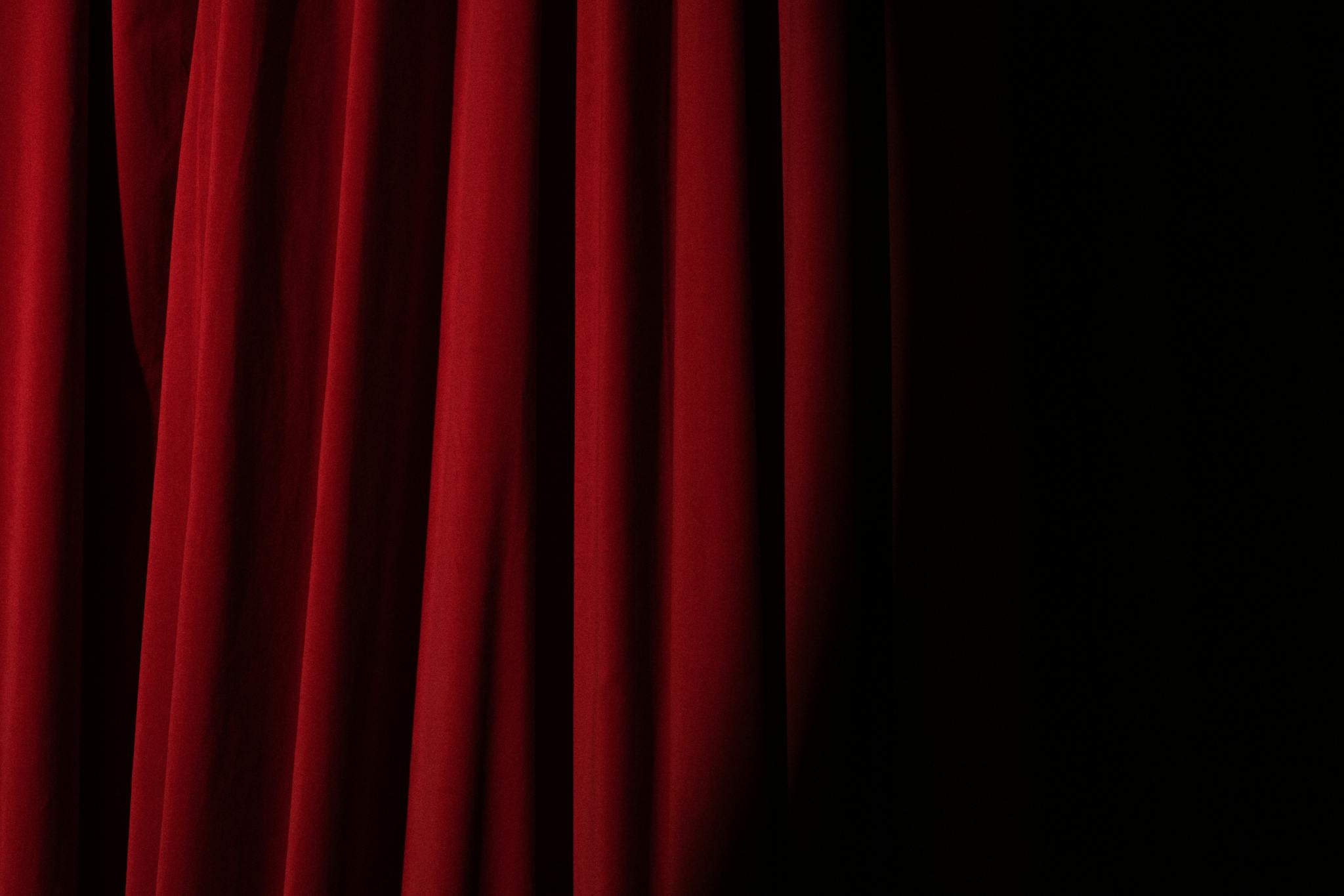 Elegant red velvet curtain with dramatic lighting perfect for theater themes.