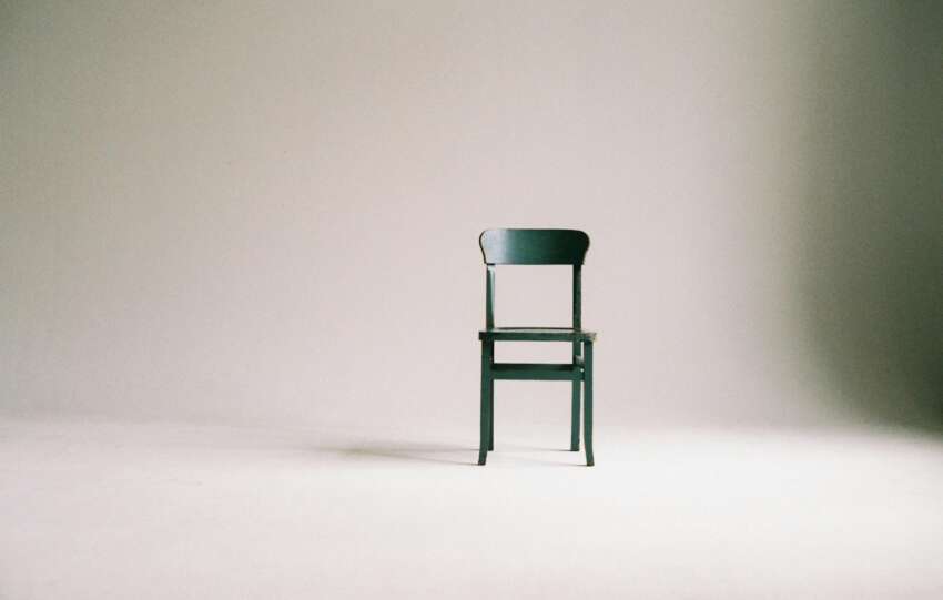 A single black chair in a minimalistic studio setting with a neutral backdrop.