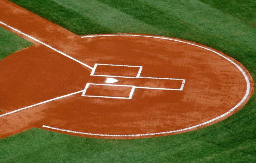 A top-down view of a baseball field's home plate area on a sunny day.