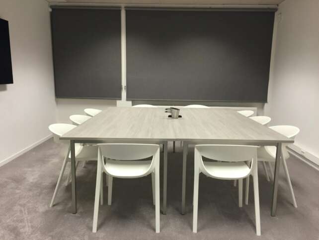 Contemporary minimalist meeting room with modern furniture and gray blinds.