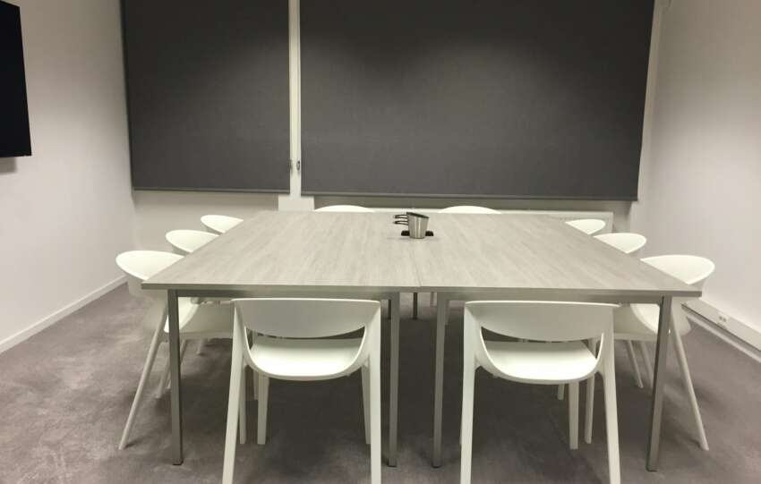 Contemporary minimalist meeting room with modern furniture and gray blinds.