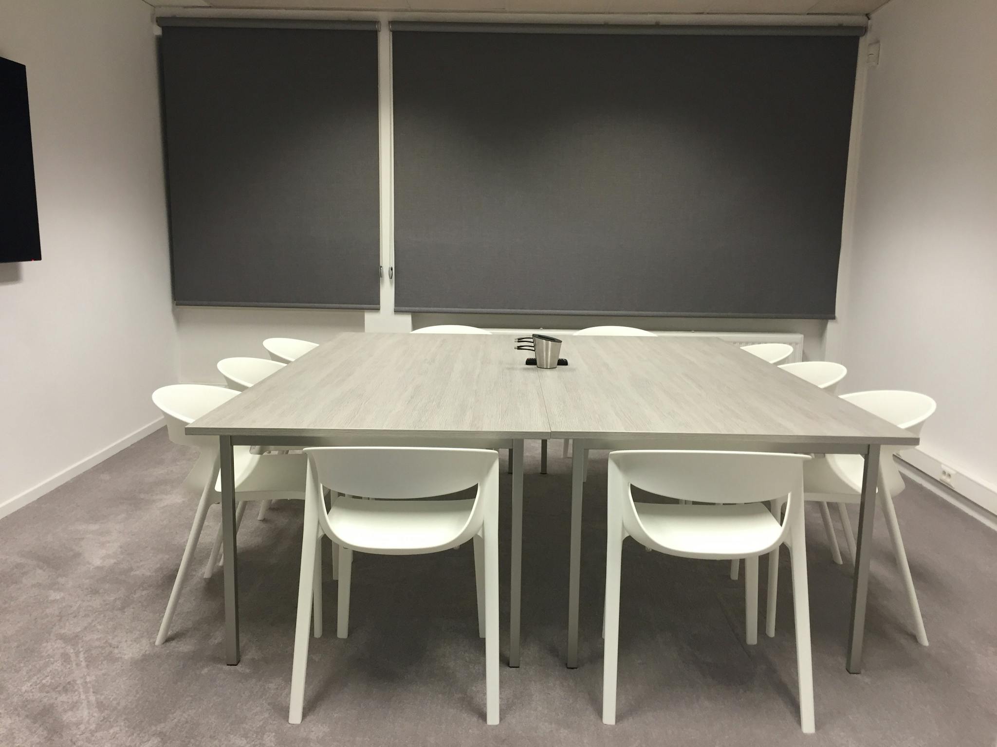Contemporary minimalist meeting room with modern furniture and gray blinds.
