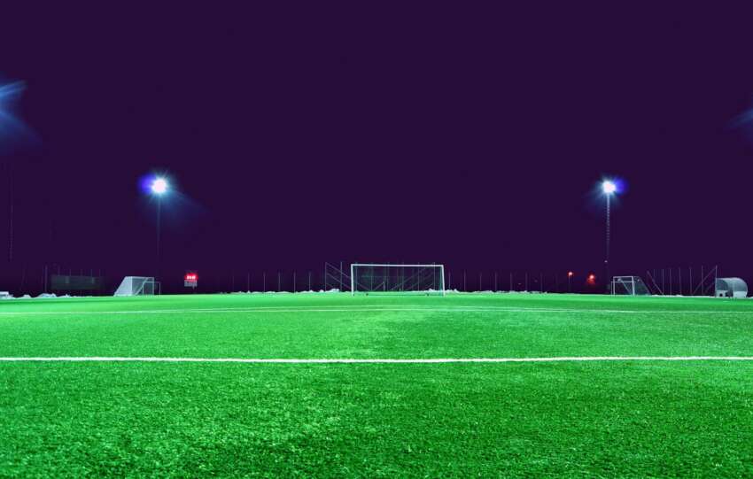 A brightly lit soccer field at night in Norrtälje, Sweden, showcasing green turf and stadium lights.