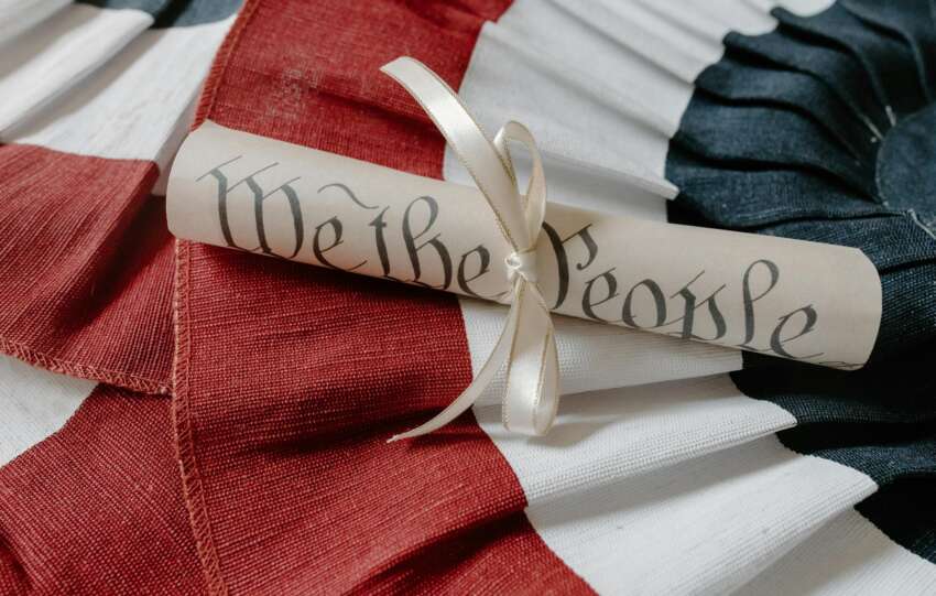 Close-up of a 'We the People' scroll on an American flag cloth background.