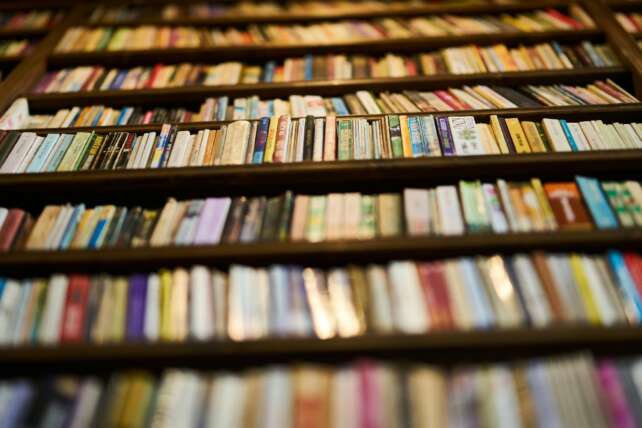 A low angle view of bookshelves filled with books in a library, showcasing a variety of spines.