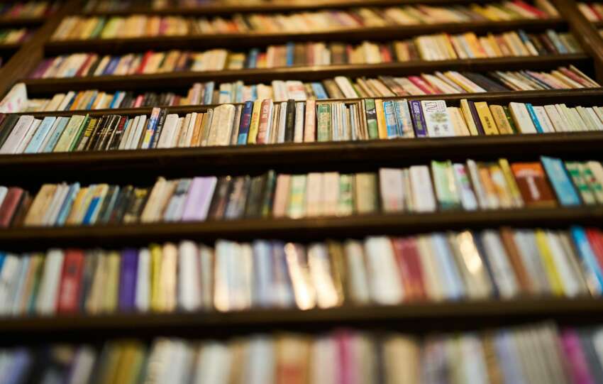 A low angle view of bookshelves filled with books in a library, showcasing a variety of spines.