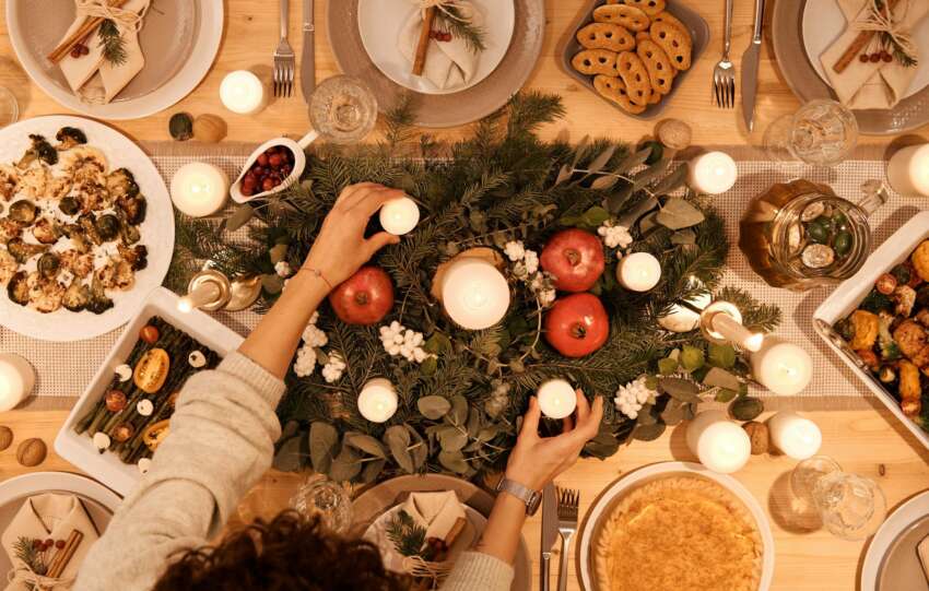 A top-down view of a festive holiday table setting with candles and decorations, perfect for Christmas or New Year's dinner.