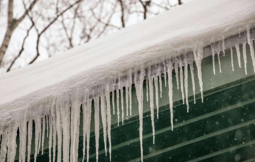 Winter scene of icicles hanging from a rooftop after heavy snowfall.