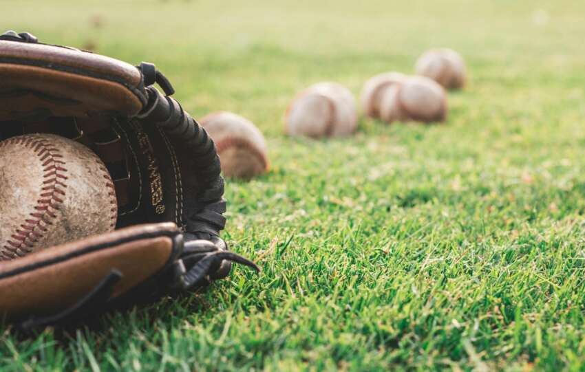A close-up of a baseball glove with balls on a green field, symbolizing outdoor sports.