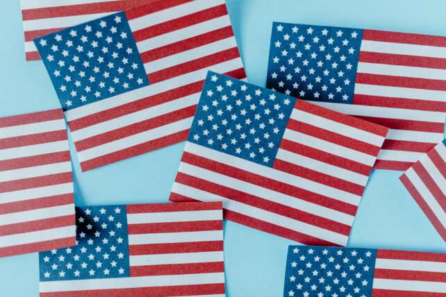 Multiple American flags on blue background symbolizing patriotism and Independence Day.
