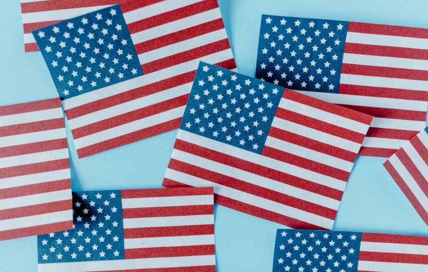 Multiple American flags on blue background symbolizing patriotism and Independence Day.