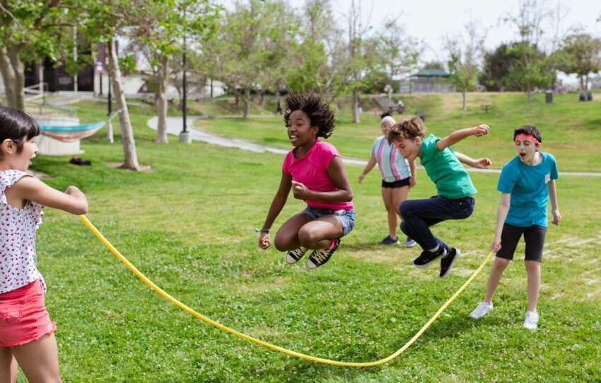Children enjoying a vibrant day playing jump rope outdoors at summer camp.