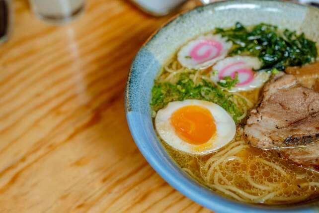 Close-up of a savory Japanese ramen bowl featuring noodles, egg, and toppings on a wooden table.