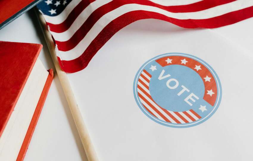 Patriotic image with American flag and vote symbol on paper.