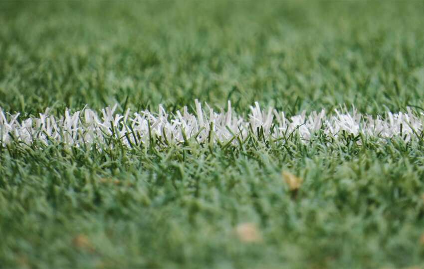 Detailed close-up of a white line on artificial green turf, perfect for sports backgrounds.