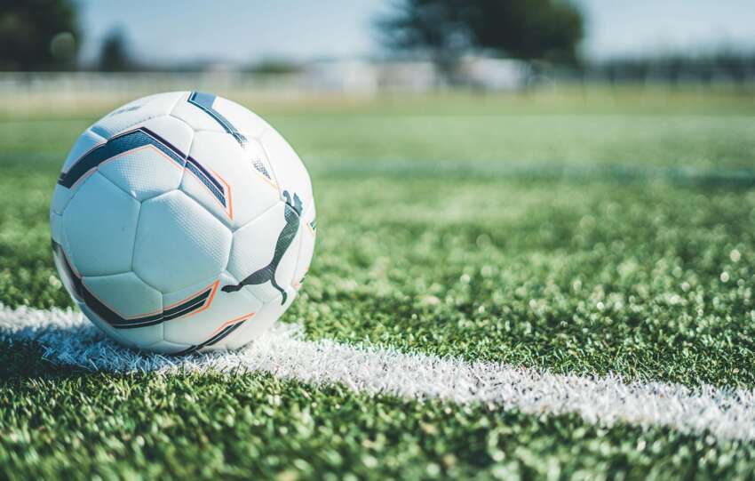 Soccer ball resting on white line of a green grass field. Perfect for sport themes.