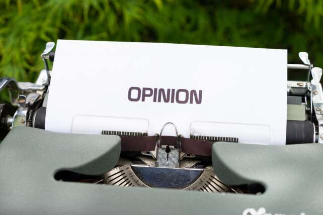 Close-up of a typewriter with paper showing the word 'Opinion' outdoors.