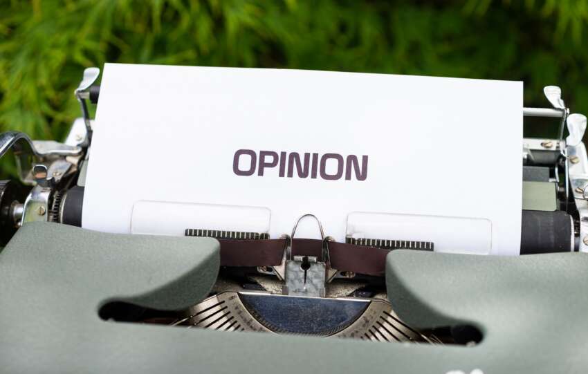 Close-up of a typewriter with paper showing the word 'Opinion' outdoors.