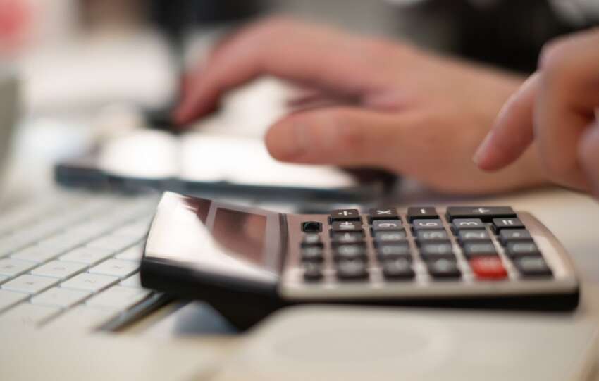 Close-up of hands using a calculator and keyboard in a financial setting, indoors.