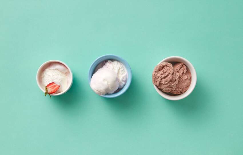 Three different ice cream flavors in cups on a mint green background. Perfect for dessert themes.