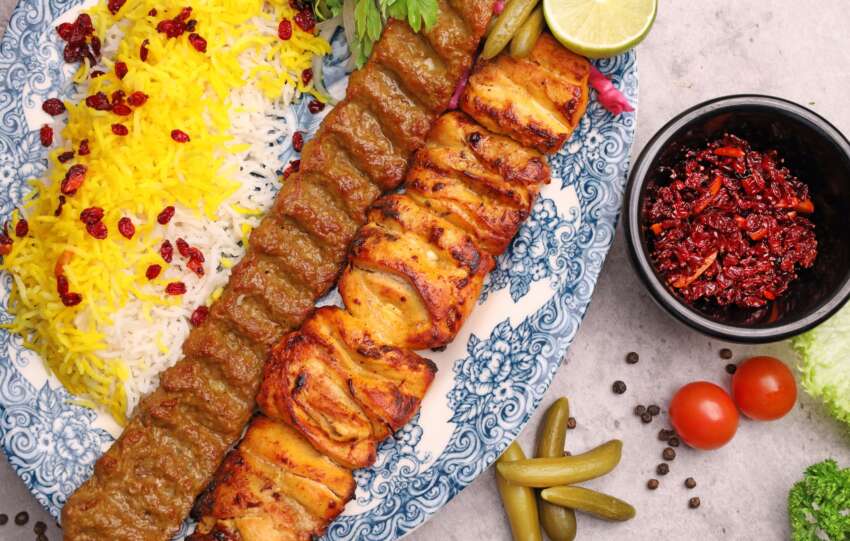 A flavorful Persian kebab dish with saffron rice, grilled meats, and vibrant sides.