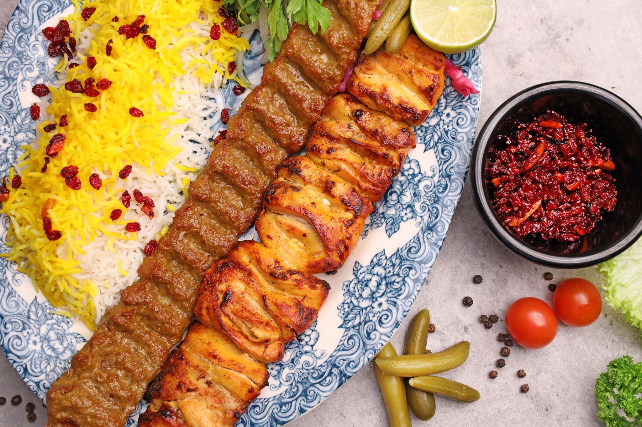 A flavorful Persian kebab dish with saffron rice, grilled meats, and vibrant sides.