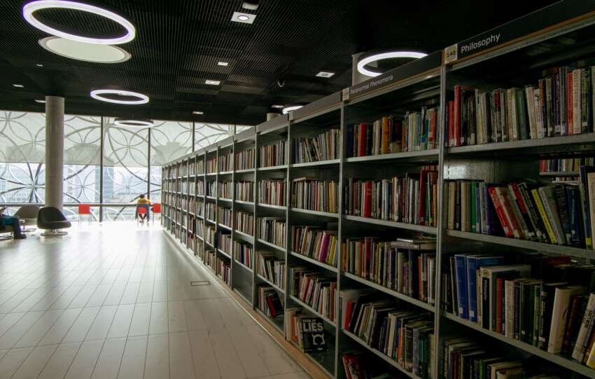 A quiet modern library interior with bookshelves and bright circular lights.