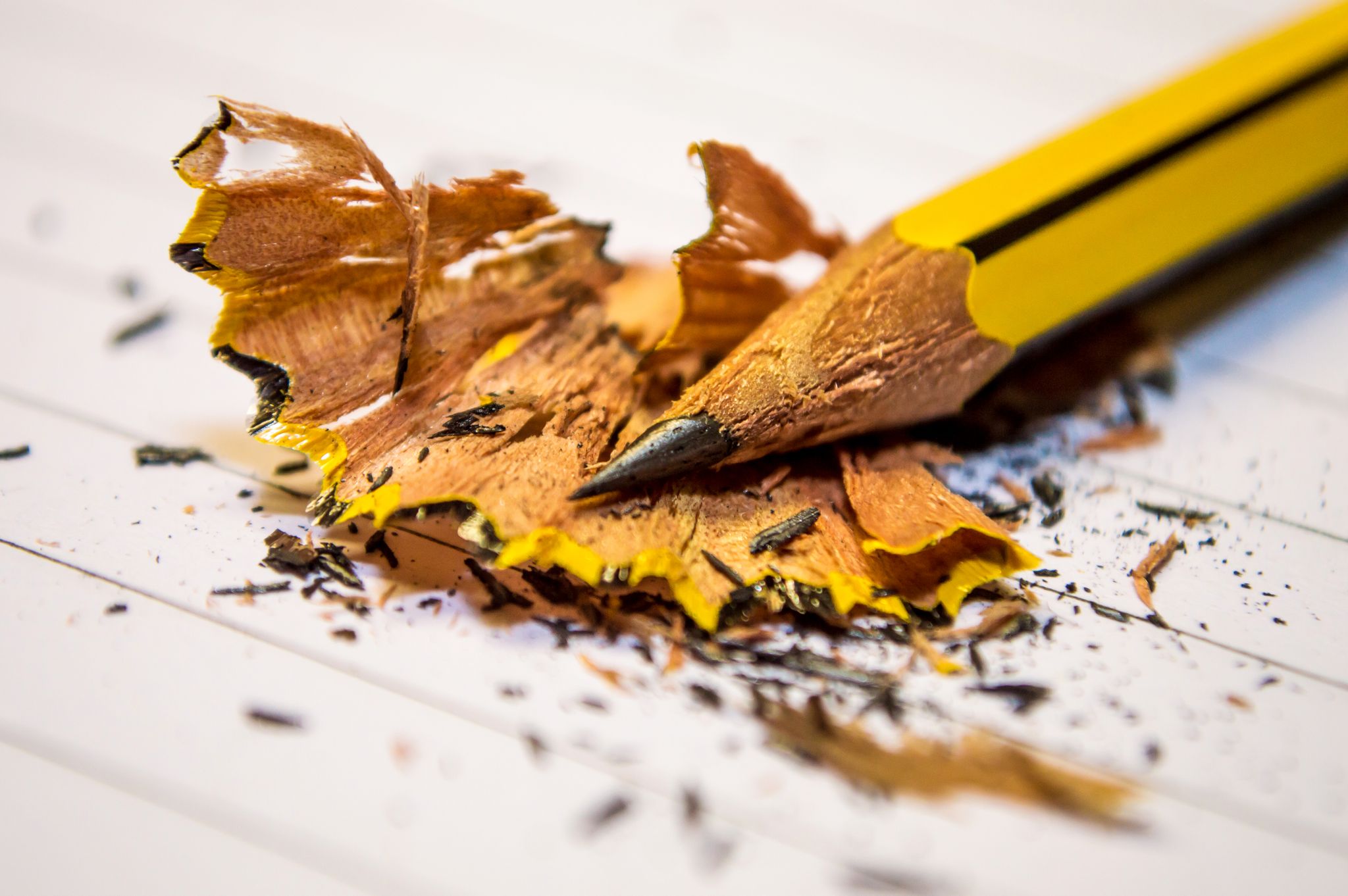 Detailed view of a sharpened yellow pencil with shavings, highlighting creative mess.