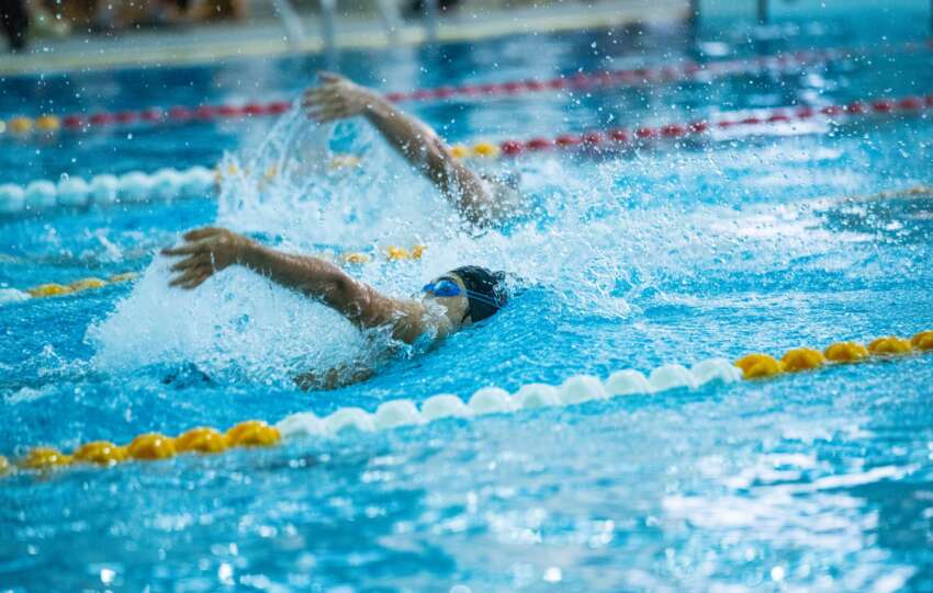 Dynamic shot of swimmers racing in a competitive swimming pool, emphasizing speed and skill.