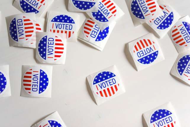 Top view set of small round stickers with flag of United Stated and I voted text scattered on white surface