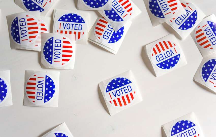 Top view set of small round stickers with flag of United Stated and I voted text scattered on white surface