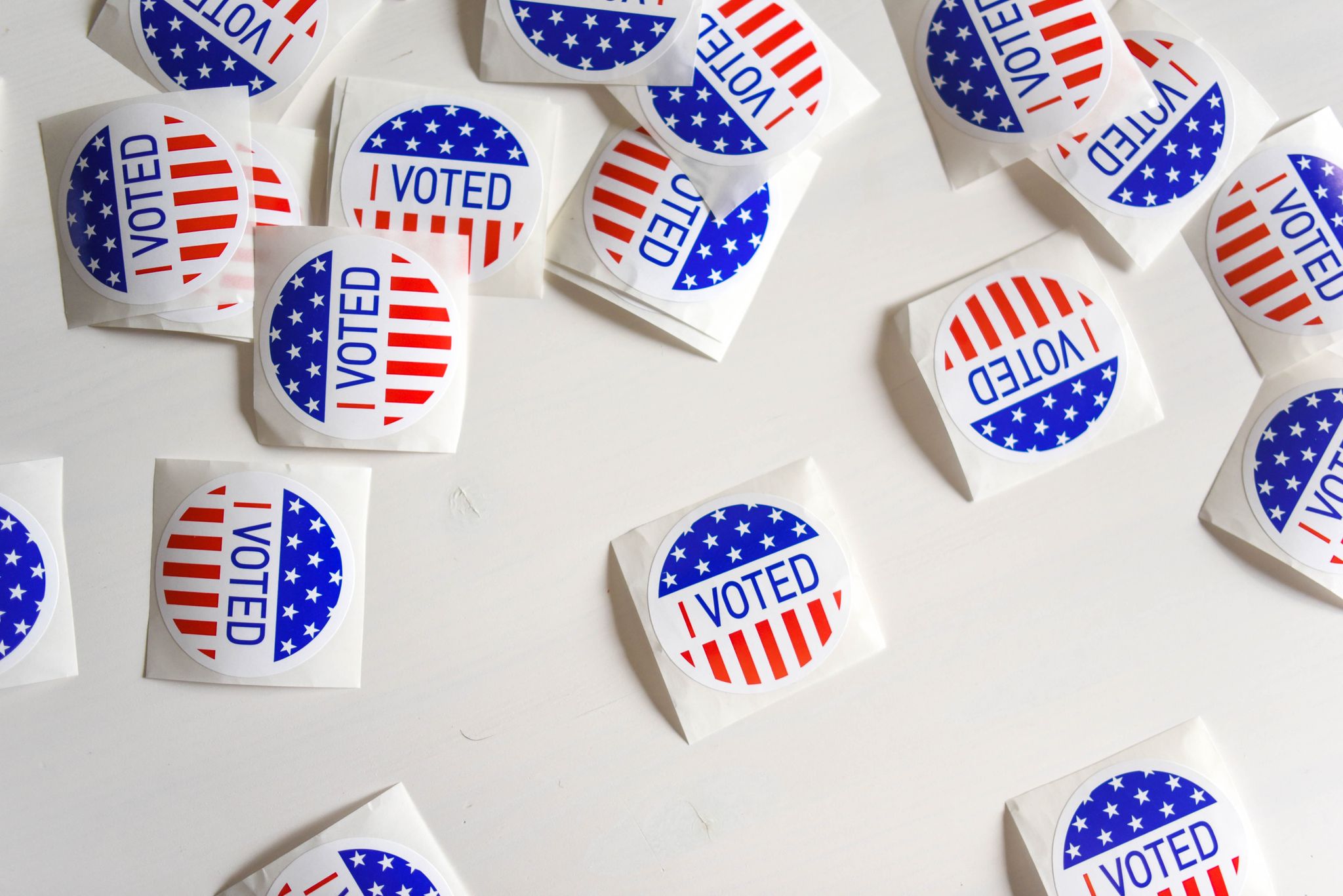 Top view set of small round stickers with flag of United Stated and I voted text scattered on white surface