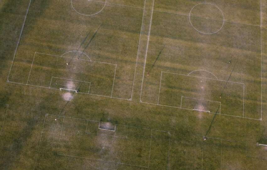 Aerial shot of soccer fields in Luton, England, showcasing green grass and goalposts.